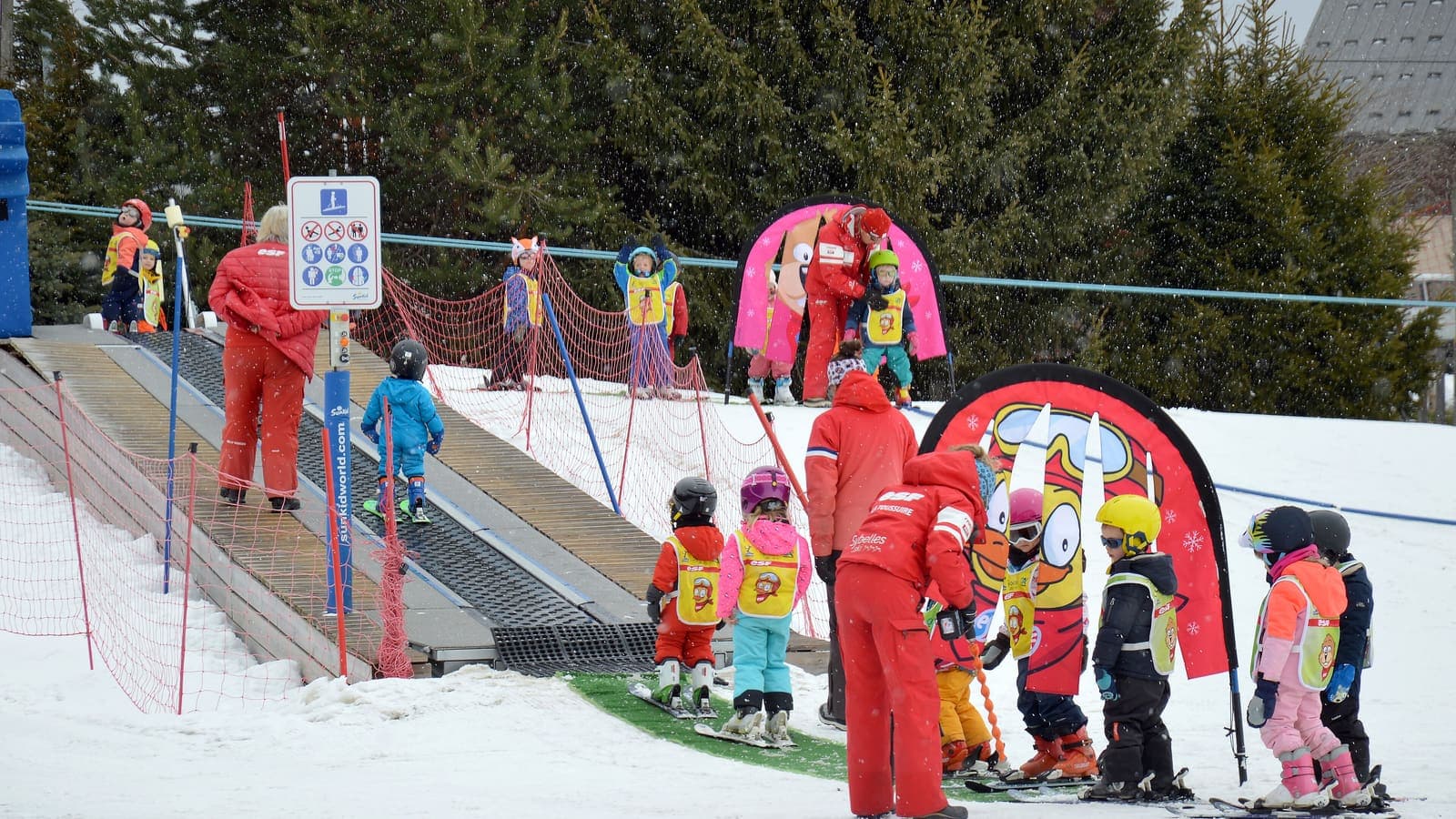 Kinder mit Skilehrern im Kinderland am Förderband